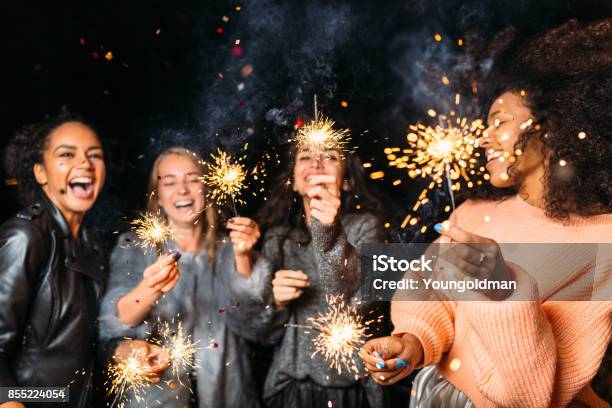 Four Happy Women Holding Sparklers Throwing Confetti Stock Photo - Download Image Now