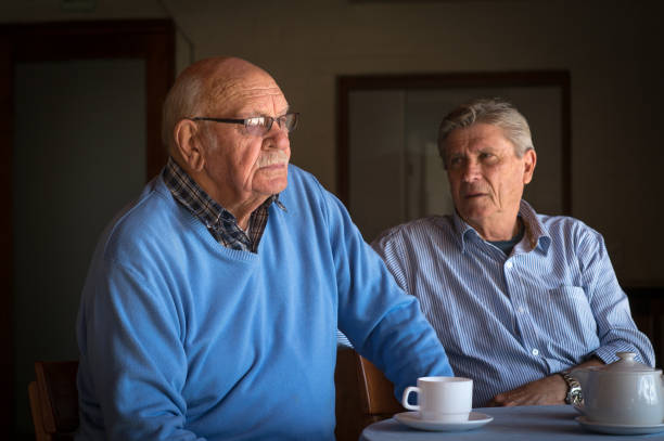 dwóch starszych mężczyzn pocieszających się nawzajem przy filiżance kawy - senior adult grandfather 70s discussion zdjęcia i obrazy z banku zdjęć