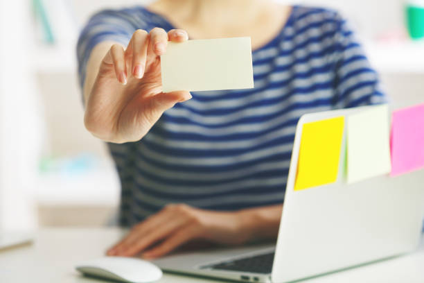istock Woman with laptop holding visiting card 855239522