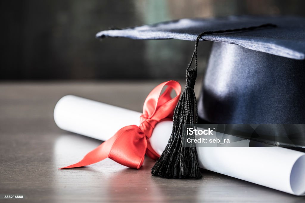 Graduation hat and diploma on table Diploma Stock Photo