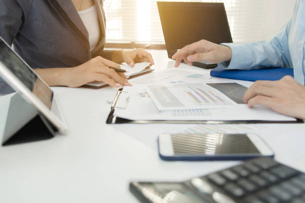 dos colegas de negocios discutir plan con datos financieros gráfico sobre mesa de oficina con ordenador portátil, co concepto de trabajo, reunión de negocios - desk corporate business business paper fotografías e imágenes de stock