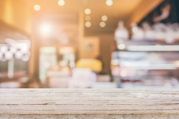 wood table top with abstract blur coffee shop background - coffee serving cafeteria worker checkout counter imagens e fotografias de stock