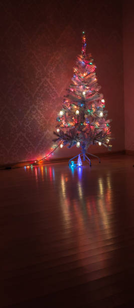istock Christmas tree with a garland in a dark room is reflected from the parquet 855263280
