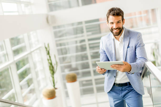 istock Portrait of confident businessman using tablet on office stairs 855273778