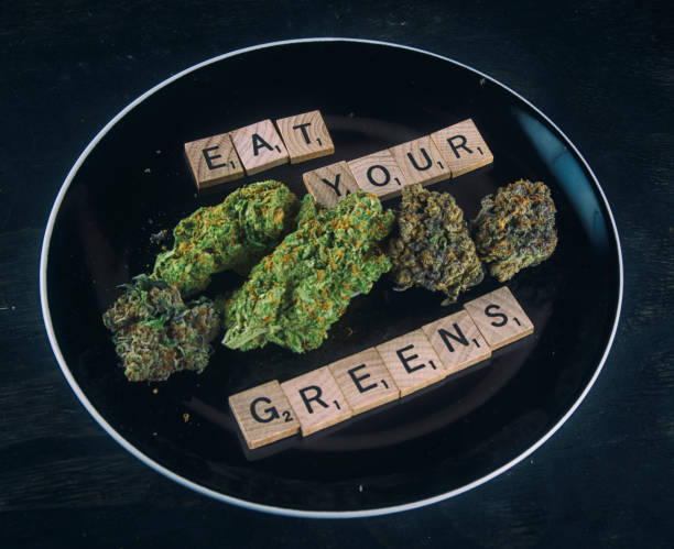 Plate with cannabis buds on black - infused medical marijuana concept stock photo
