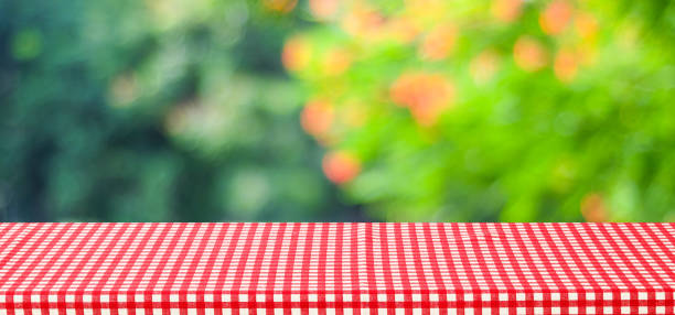 istock Empty table with red tablecloth over blur green tree and bokeh background, for food and product display montage background, banner 855280638