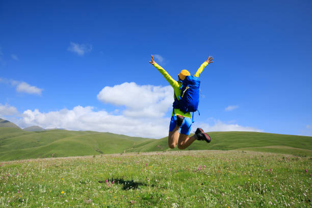 istock cheering young woman jumping in grassland mountain top 855281064