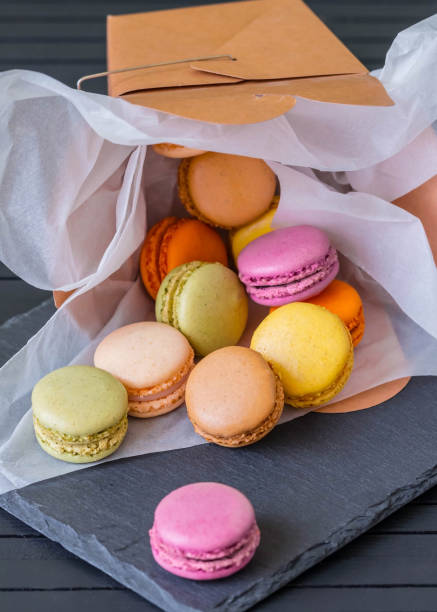 dropped from craft box with colorful macarons on the black background. craft box filled with macaroons. french macaroons. rainbow. dessert menu. - craft chocolate candy black box imagens e fotografias de stock