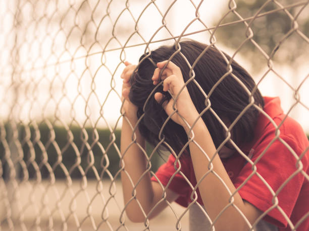 istock Retro style sad boy behind fence mesh netting. Emotions concept - sadness, sorrow, melancholy. 855287282