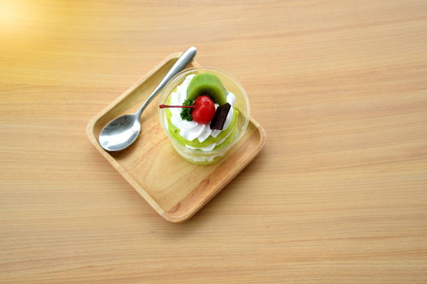 Three layer of green sofe cake with whipping cream and toping with chocolate cherry  and kiwi on wooden table Three layer of green sofe cake with whipping cream and toping with chocolate cherry  and kiwi on wooden table sofe stock pictures, royalty-free photos & images