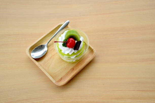 Three layer of green sofe cake with whipping cream and toping with chocolate cherry  and kiwi on wooden table Three layer of green sofe cake with whipping cream and toping with chocolate cherry  and kiwi on wooden table sofe stock pictures, royalty-free photos & images