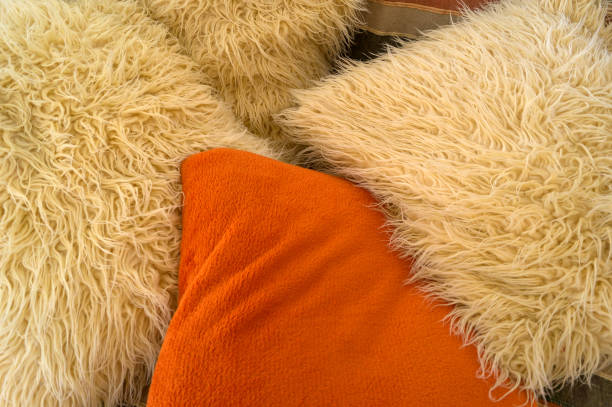 istock Beige and orange artificial wool cushions on the couch 855301848