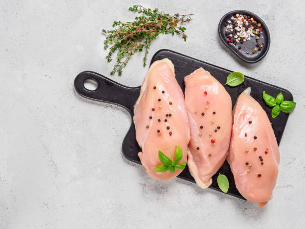 Raw chicken breast with fresh basil and thyme on black cuttingboard, copyspace Raw chicken breast with fresh basil and thyme on black cuttingboard. Raw chicken fillet on gray cement background. Copy space. Top view or flat lay. pink pepper spice ingredient stock pictures, royalty-free photos & images