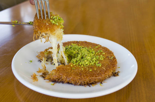 sobremesa turca kunefe, kunafa, kadayif com pistache em pó e queijo quente comido um doce - künefe - fotografias e filmes do acervo