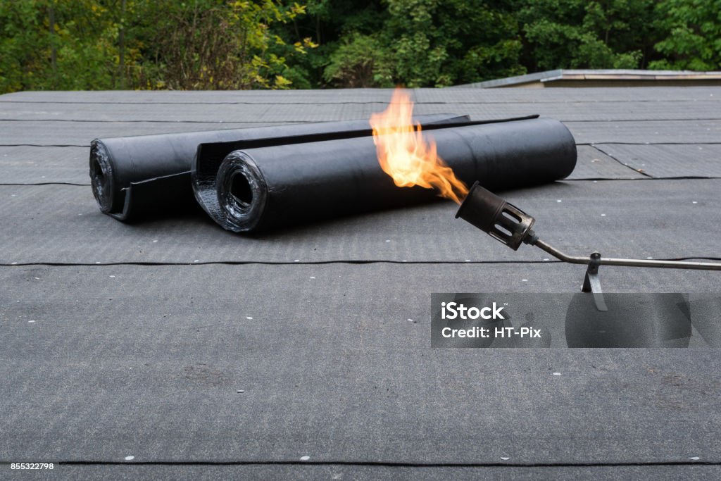 Heating and melting bitumen roofing felt Flat roof installation Heating and melting bitumen roofing felt Flat roof installation. Rooftop Stock Photo