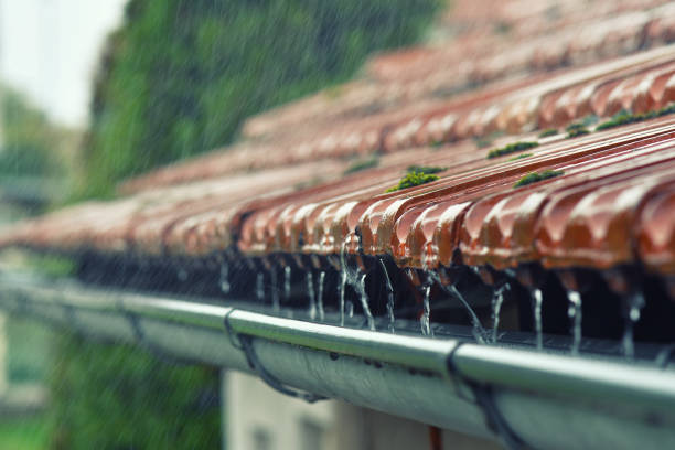 Drops of water flow into the eaves on the house in the rain. stock photo