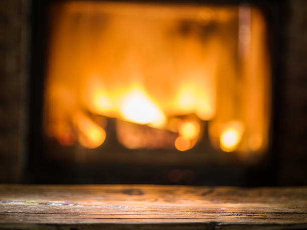 istock Old wooden table and fireplace with warm fire on the background. 855327226