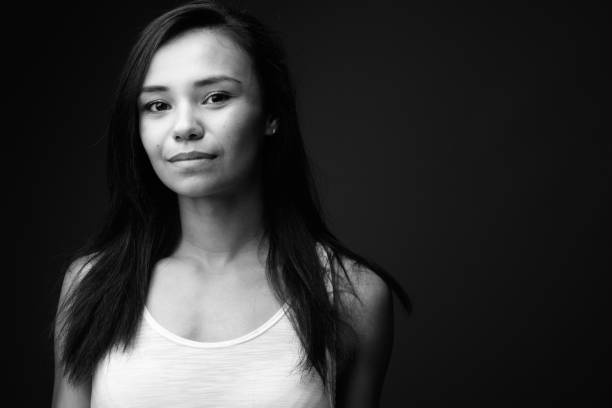 Studio shot of young Asian woman against black background in black and white Studio shot of young Asian woman against black background in black and white horizontal shot sleeveless top stock pictures, royalty-free photos & images