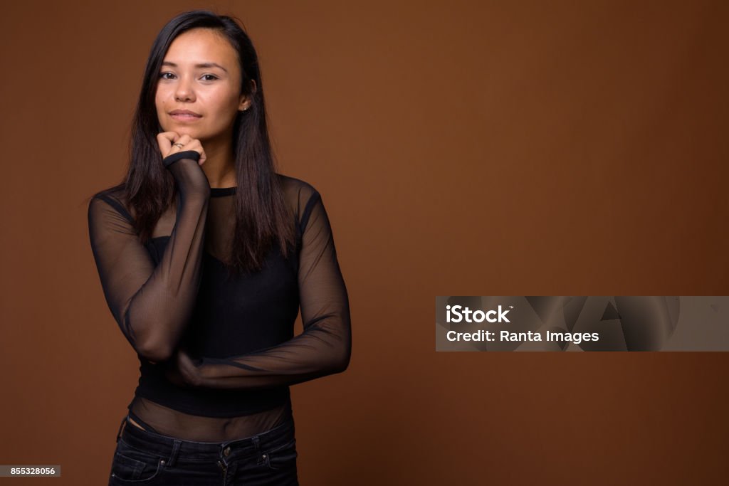 Studio shot of young Asian woman wearing black long sleeved shirt with sheer fabric against colored background Studio shot of young Asian woman wearing black long sleeved shirt with sheer fabric against colored background horizontal shot Shirt Stock Photo