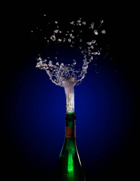 istock champagne bottle explosion with cork popping splash against a dark background with blue to black gradient, copy space 855333522