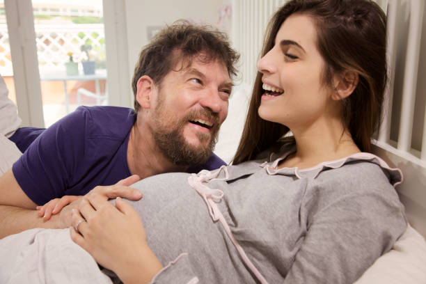 istock Man making laugh pregnant woman in bed 855336472