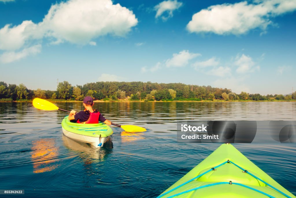 Boy in life jacket on green kayak Boy in life jacket on green kayak. Sunny day on wonderful lake. Summer time Kayaking Stock Photo