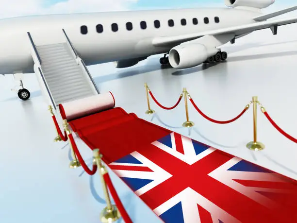 Photo of Red carpet with flag of Britain and velvet ropes laid in front of private jet door