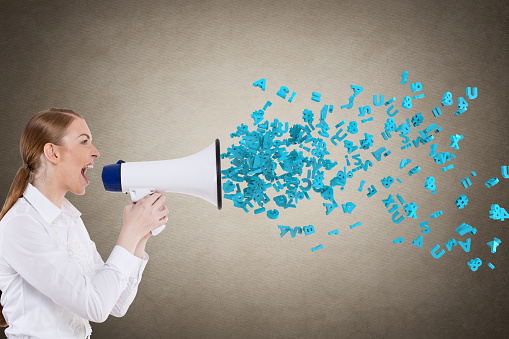 Businesswoman screaming into megaphone spilling out letters and numbers