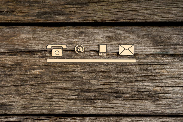 Contact and communication icons, telephone, at sign, mobile and mail, on textured rustic wooden boards.