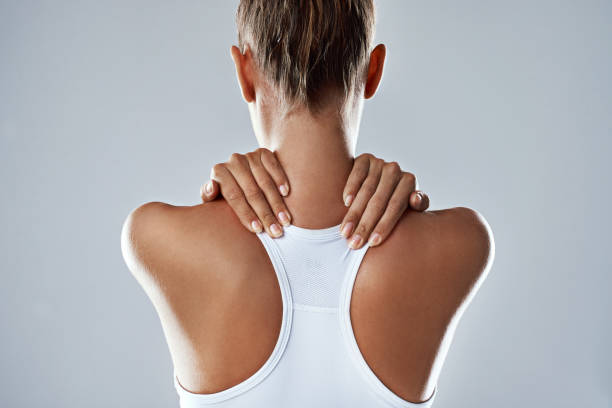 Feeling a little strain in her neck Studio shot of an athletic young woman holding her neck in pain against a grey background tetanospasmin stock pictures, royalty-free photos & images