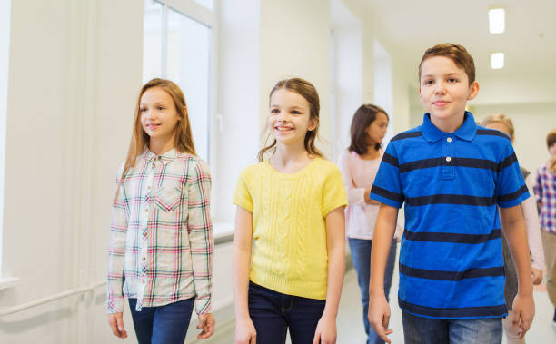 istock group of smiling school kids walking in corridor 855372450