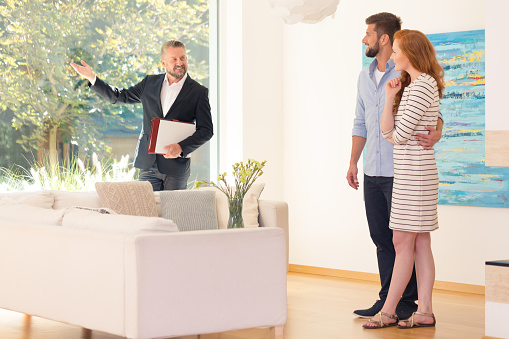 Real estate agent showing home interior for sale to young couple