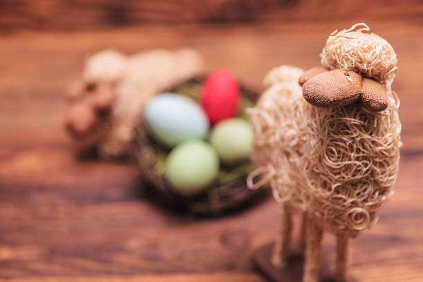 easter toy sheep in fron of egg basket on old wood background