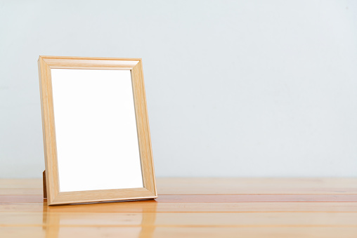 Empty wood photo frame on bright wooden table with copy space, picture memory. sweet tone.