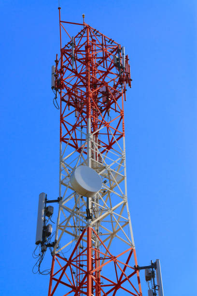 istock Mobile phone communication antenna tower with satellite dish on blue sky background 855391164