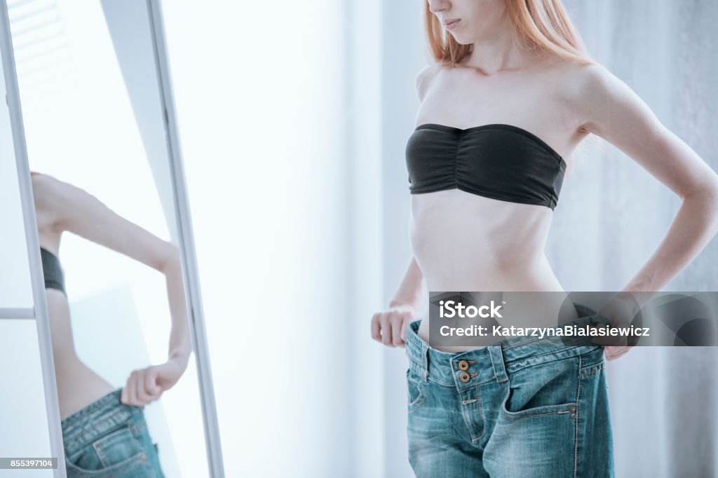 Woman becoming too undersized Woman becoming too undersized for her jeans due to an extensive and unhealthy diet Women Stock Photo