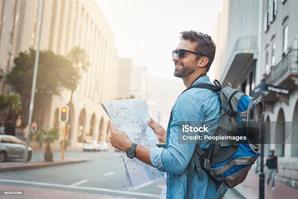 There's so much to see Shot of a young man looking at a map while touring a foreign city Travel Stock Photo