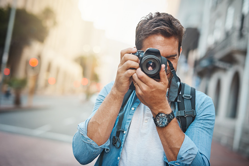 Cropped shot of a young man taking photos while exploring a foreign city