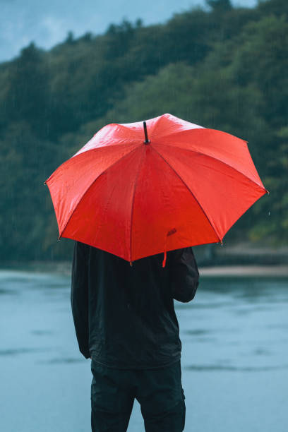 istock Man with red umbrella contemplates on rain 855421430