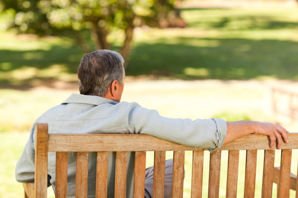 istock Elderly man sitting on the bench with his back to the camera 855421666