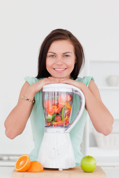 istock Smiling young woman posing with a blender 855429830
