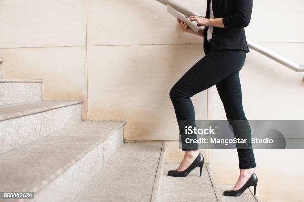 Businesswoman Walking Upstairs And Using Touchpad Stock Photo - Download Image Now - High Heels, Staircase, Walking
