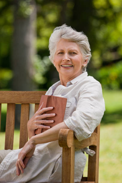istock Retired woman reading a book on the bench 855442834