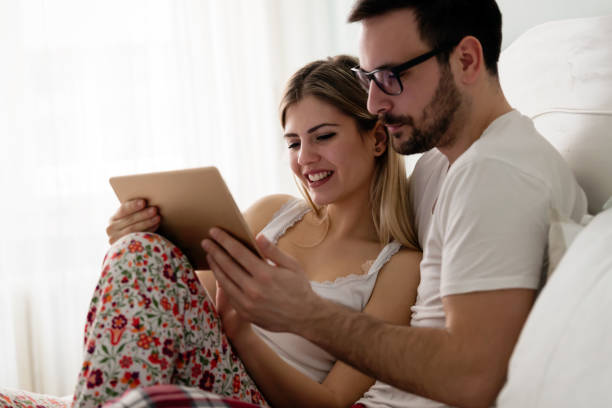 istock Young attractive couple using tablet in bedroom 855447590