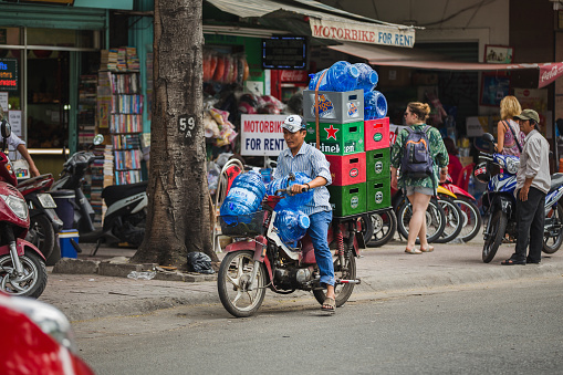 Ho Chi Minh City, Vietnam - January 02, 2016: One man carrying gallons of water and boxes of beer on a motorcycle in Ho Chi Minh City, Vietnam.