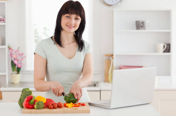 istock Smiling brunette woman cooking while relaxing with her laptop 855464088