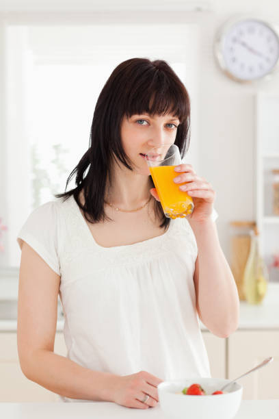 istock Charming brunette drinking a glass of roange juice while standing 855470668