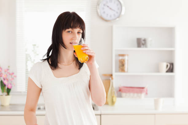 istock Gorgeous brunette drinking a glass of orange juice while standing 855470788