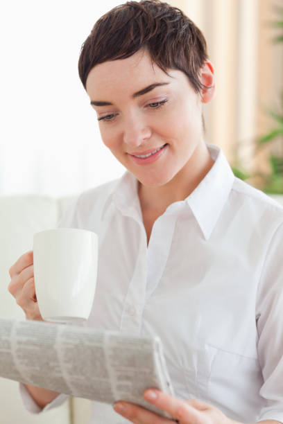 istock Cute woman with a cup and a newspaper 855470838