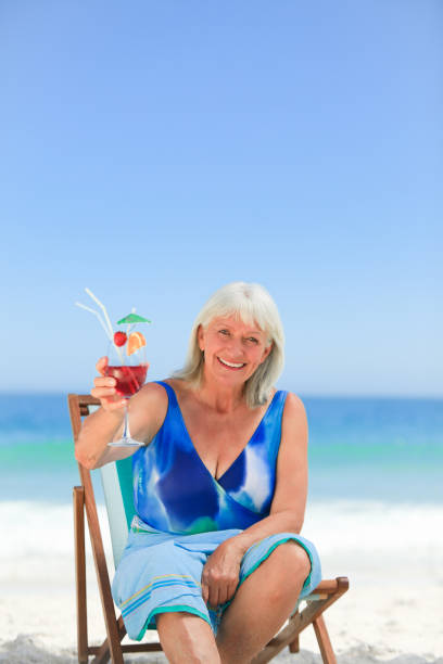 istock Elderly woman drinking a cocktail on the beach 855471762